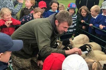 A speaker talking to children next to sheep